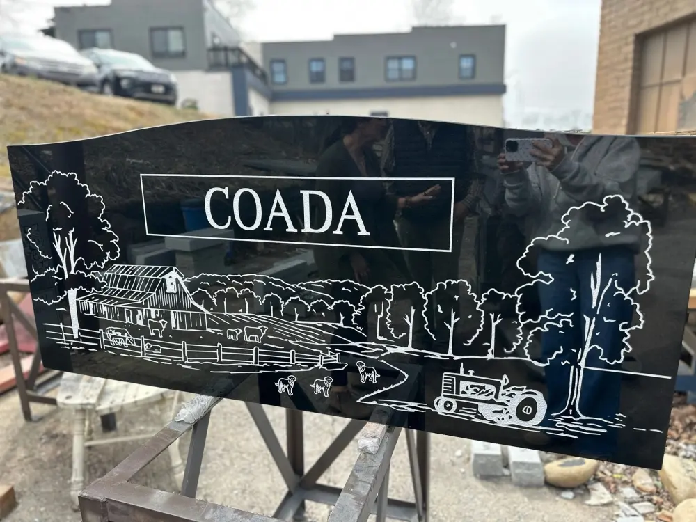Black granite companion monument with etched scenes and portraits, Coada