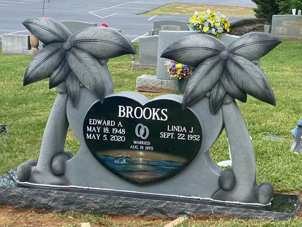 Black granite heart monument between two carved palm trees, Brooks